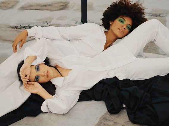 2 women lying next to each other on opposite directions, wearing both black clothings